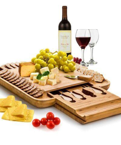 Bambusowa deska do serów z nożami. Kompozycja serów, wina, winogron na desce.